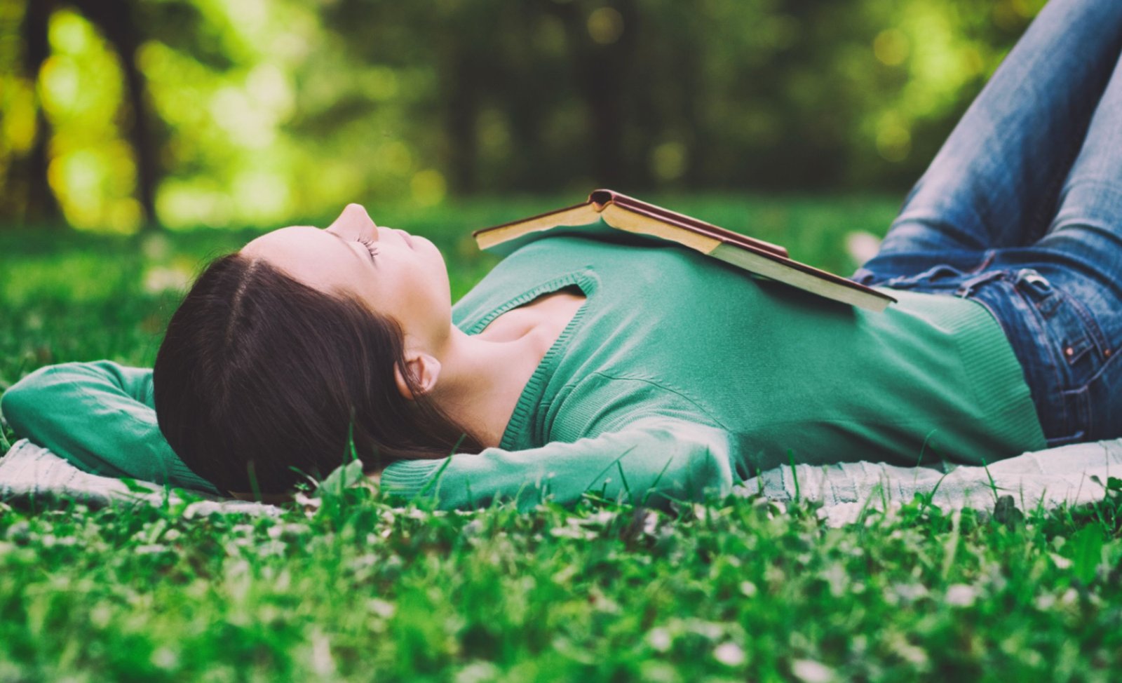 Person resting on grass with a book